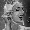 Woman Wearing Flowered Bathing Cap and Applying Mascara as Water Showers Around Her - Гьен Мили (Gjon Mili)